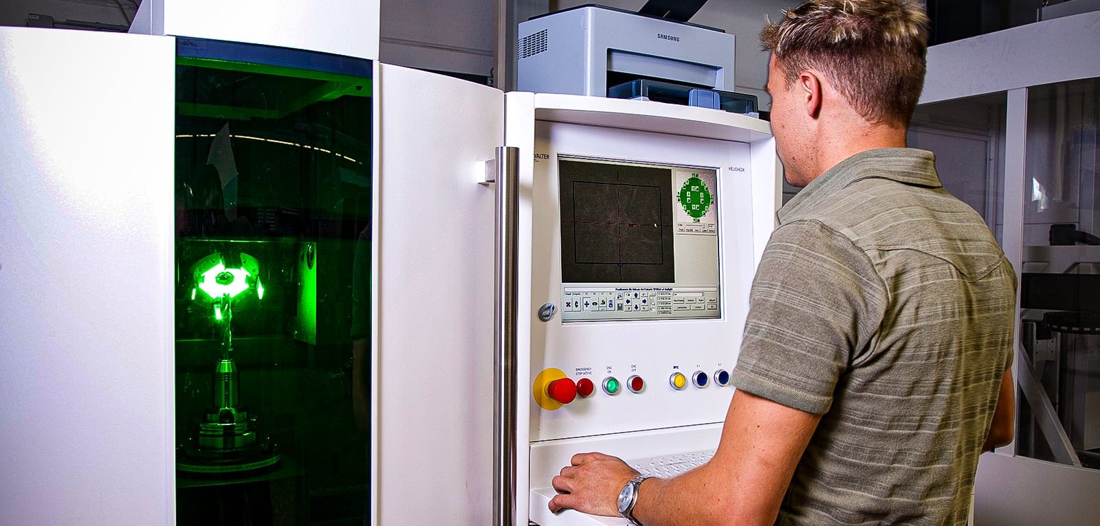 Mitarbeiter bedient die optische Messmaschine, Werkzeug wird unter Grünlicht vermessen